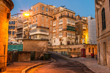 Valletta, Malta - The traditional maltese houses with balconies and walls of Valletta illuminated before sunrise
