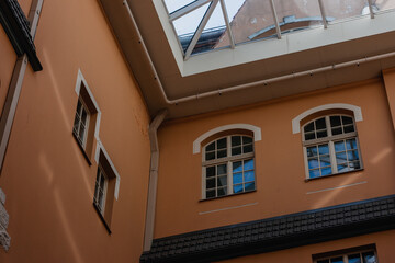 Orange wall of residential house with wooden windows and panes and rainwater drain pipes and glass roof.
