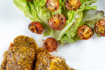 Baked dijon mustard salmon with cherry tomatoes and lettuce in white wine sauce