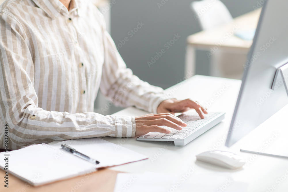 Poster unrecognizable female employee working on computer at desk in office, cropped image of lady typing o