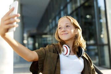 Teen smiling girl making selfie on summer day or having mobile conversation on smartphone,portrait
