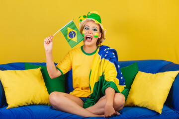 Caucasian woman, redhead, brazil soccer fan, brazilian, on couch holding brazil flag