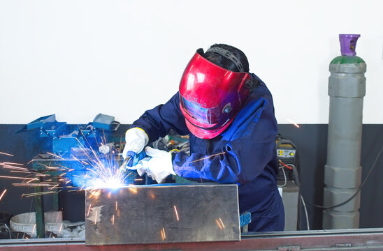 worker woman with gloves welding metal with helmet and overalls