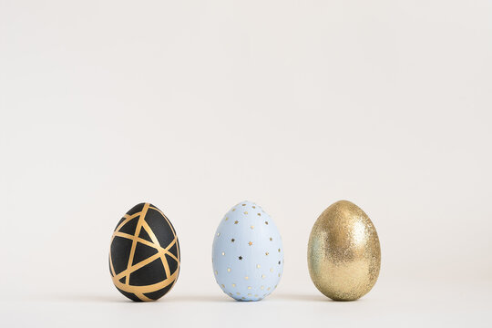 Three Easter golden decorated eggs on white background. Minimal easter concept. Happy Easter card with copy space for text. Top view, flatlay.