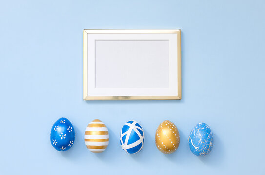 Frame with gold decorated easter eggs with copy space for text on blue background. Minimal Happy Easter concept. Top view, flatlay