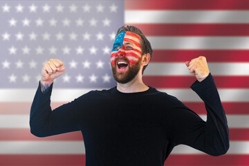 fans of the usa soccer team celebrate winning a match during the world championships; happy usa football fans with painted faces and the usa flag in the background