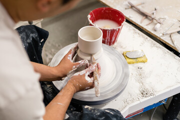 Centre clay and throw pots on the pottery wheel. Muddy work table and handmade clayware. Wet...