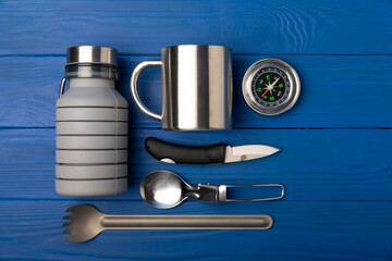 Set of tourist equipment on a blue texture background. EDC set. Flat layout. Camping plate, mug,...