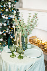 The table is set near the Christmas tree for a romantic New Year's dinner. New Year's festive dinner.