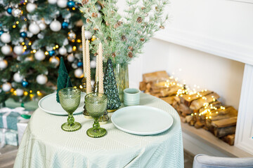 The table is set near the Christmas tree for a romantic New Year's dinner. New Year's festive dinner.