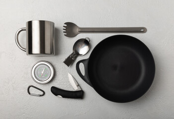 Set of tourist equipment on a white textured background. EDC set. Flat layout. Camping plate, mug, bottle, spoon and compass.