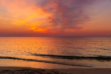 Krajobraz morski. Widok z zachodem słońca i lekkimi falami na piaszczystej plaży.