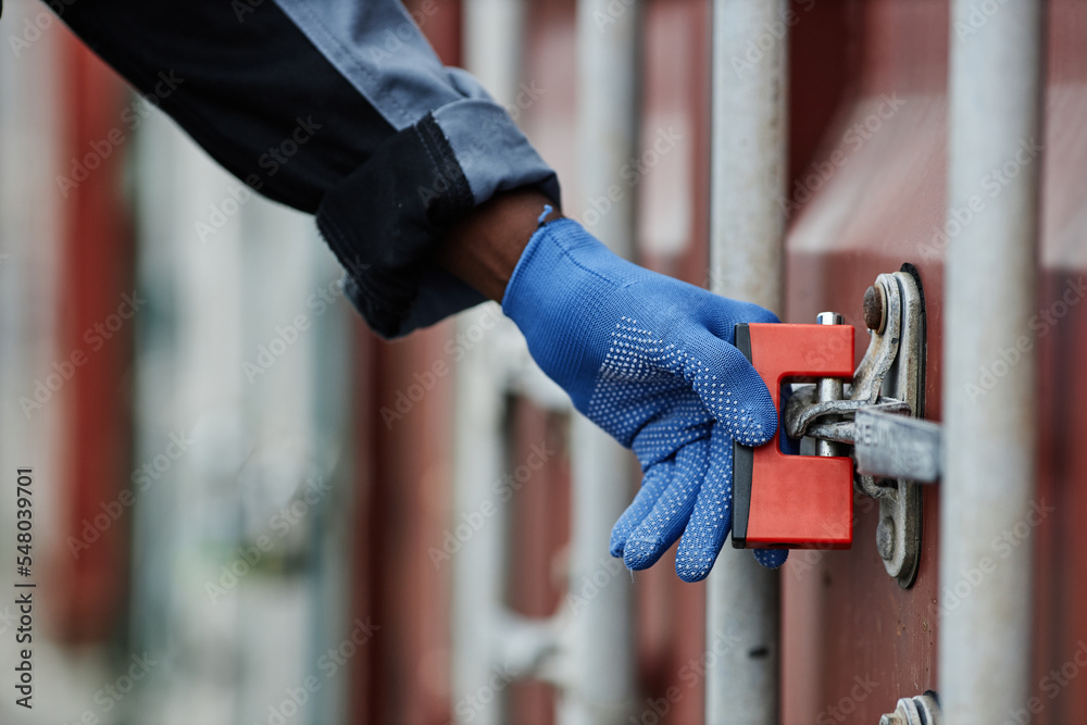 Wall mural Close up of worker opening lock on container door in shipping docks, copy space