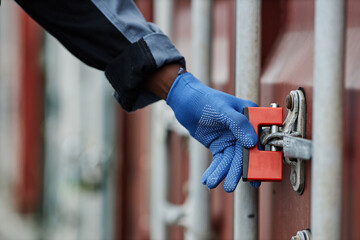 Close up of worker opening lock on container door in shipping docks, copy space - obrazy, fototapety, plakaty