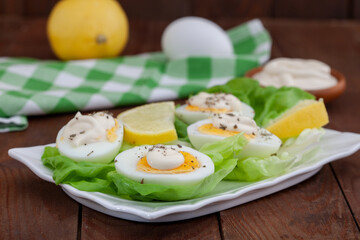 Appetizer of boiled eggs with mayonnaise and spices. Eggs with mayonnaise on green lettuce leaf.