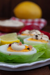 Appetizer of boiled eggs with mayonnaise and spices. Eggs with mayonnaise on green lettuce leaf. Vertial image.