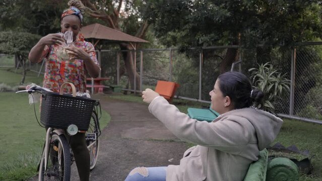 Video de una mujer afro caribe&ntilde;a vendiendo sus productos a una mujer sentada en un parque de su comunidad