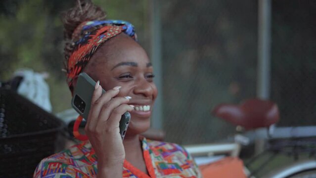 Primer plano de una mujer afro caribeña hablando por celular muy sonriente 