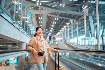 Happy attractive asian woman passenger traveler with a yellow suitcase at the modern airport terminal, copy space, Tourist journey trip concept