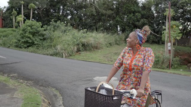 Imagen en video de una mujer afro caribe&ntilde;a esperando sobre una bicicleta y ofreciendo sus productos muy feliz en la calle