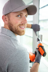 portrait of construction worker using drill on double-glazed window