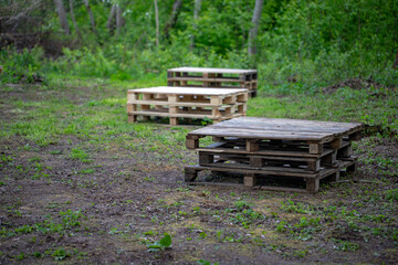 wooden palettes in field near green forest