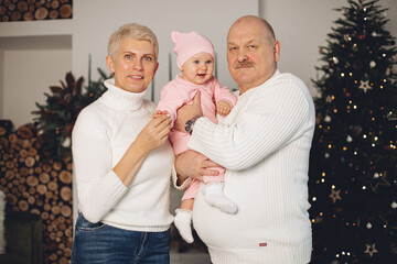 Old caucasian woman celebrates Christmas with her husband and little granddaughter