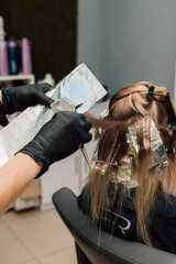 A professional hairdresser applies dye to a client's hair. Hair coloring