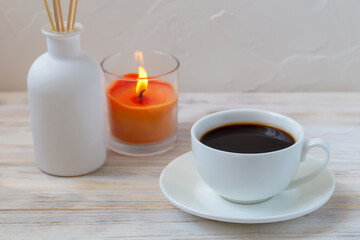 Cup of coffee, aroma reed diffuser and candle