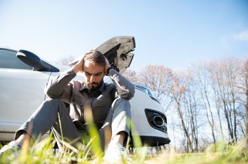 Sad driver holding his head having engine problem standing near broken car on the road. Car breakdown concept