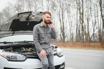 Sad man on the road next to the broken car