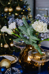 Festive Christmas table with flowers and candles. Atmosphere of New Year and Christmas. Beautiful happy lights. Serving a gala dinner
