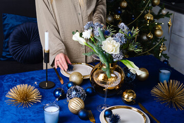 A woman decorates the Christmas table. Festive atmosphere of New Year and Christmas. Beautiful...
