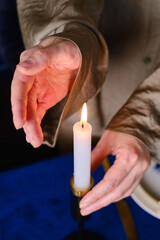 A girl holds a lit candle in her hands in a Christmas apartment. Candle close-up. Relaxation and zen atmosphere
