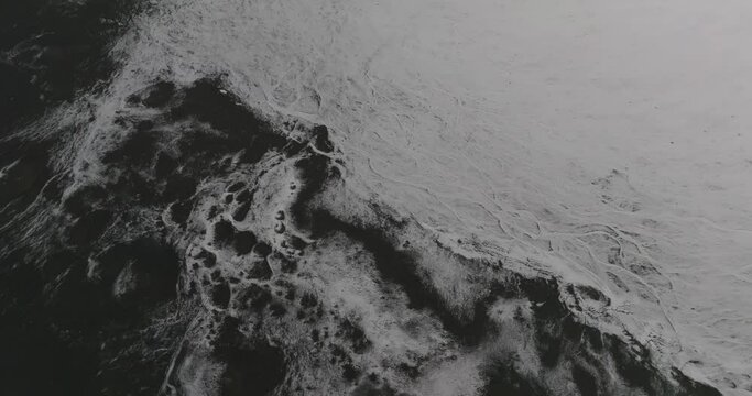 aerial view on textured moon like surface of black volcanic soil covered with snow and craters