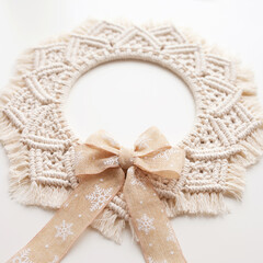 Christmas decor. Macrame wreath for Christmas and the new year on a white decorative plaster wall. Natural cotton thread, linen tape. Eco decor for home
