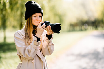 young beautiful girl is resting in nature with camera. woman photographer walking in the park on an autumn day