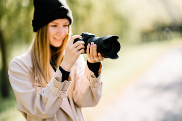 young beautiful girl is resting in nature with camera. woman photographer walking in the park on an autumn day