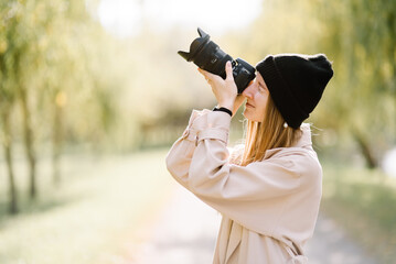 young beautiful girl is resting in nature with camera. woman photographer walking in the park on an autumn day