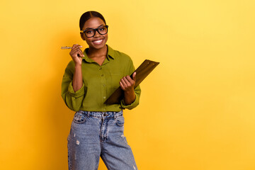 Portrait of attractive cheerful girl holding clipboard signing paper copy space isolated over...