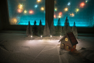 Christmas and New Year miniature house in the snow at night with fir tree. Little toy house on snow...