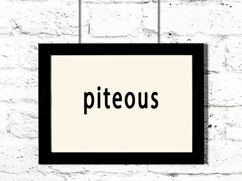 Black frame hanging on white brick wall with inscription piteous