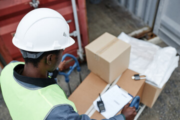 Top view at worker pushing cart with boxes at shipping docks, copy space