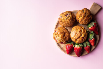Strawberry muffins on a wooden board on a pink background. - 548052595