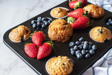 Assorted blueberry and strawberry muffins in a baking tin. Close up. - 548052700