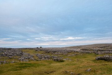 Fototapeta na wymiar Landscape where a green meadow with rocks meets the cloudy sky in Ireland.