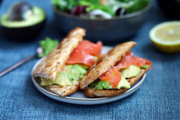 Salmon sandwich with avocado and lettuce.