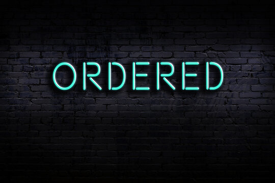 Neon sign. Word ordered against brick wall. Night view