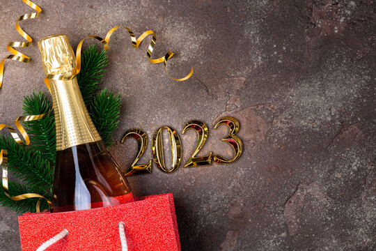 Happy new year 2023 background. New year holidays card with shopping bag with bottle of сhampagne, festive decorations. Gifts, present for New Year 2023. Copy space
