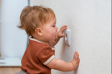 Children's curiosity is a danger to life -  baby girl touching a socket.